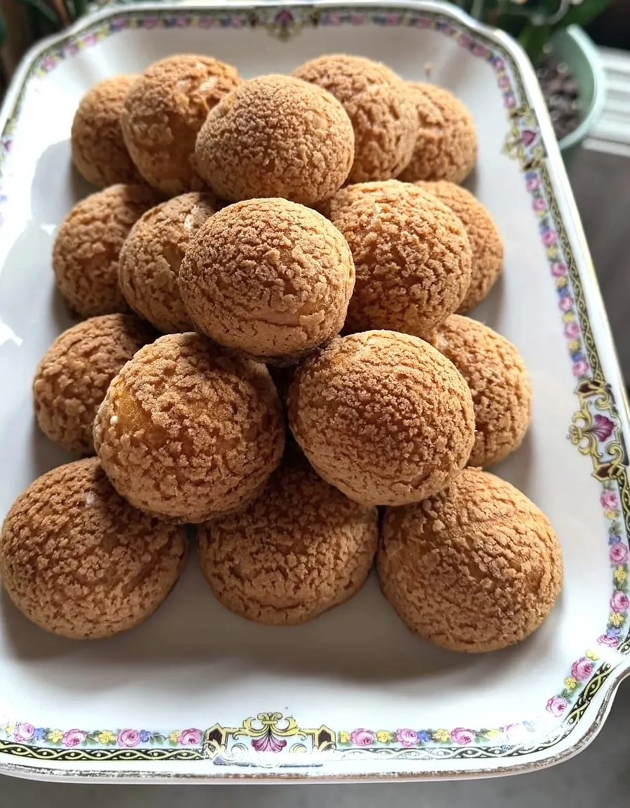 Choux au craquelin empilés en pyramide sur un plat ancien à bord fleuri