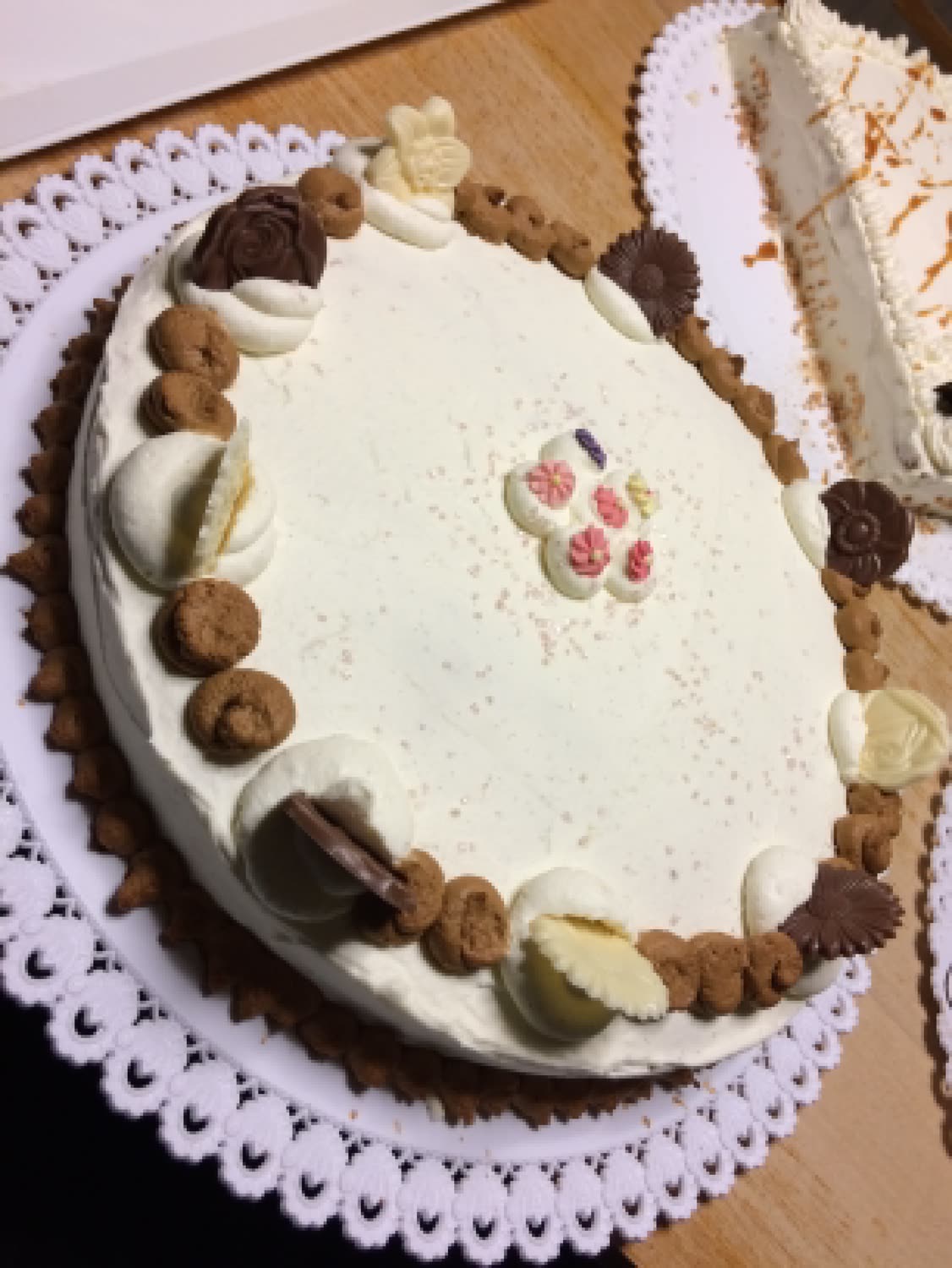 Grand gâteau ovale à la crème café, bordé de biscuits et de fleurs en chocolat