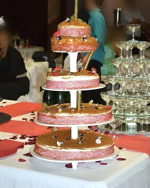 Wedding cake nu à quatre étages garni de fruits rouges et de fleurs
